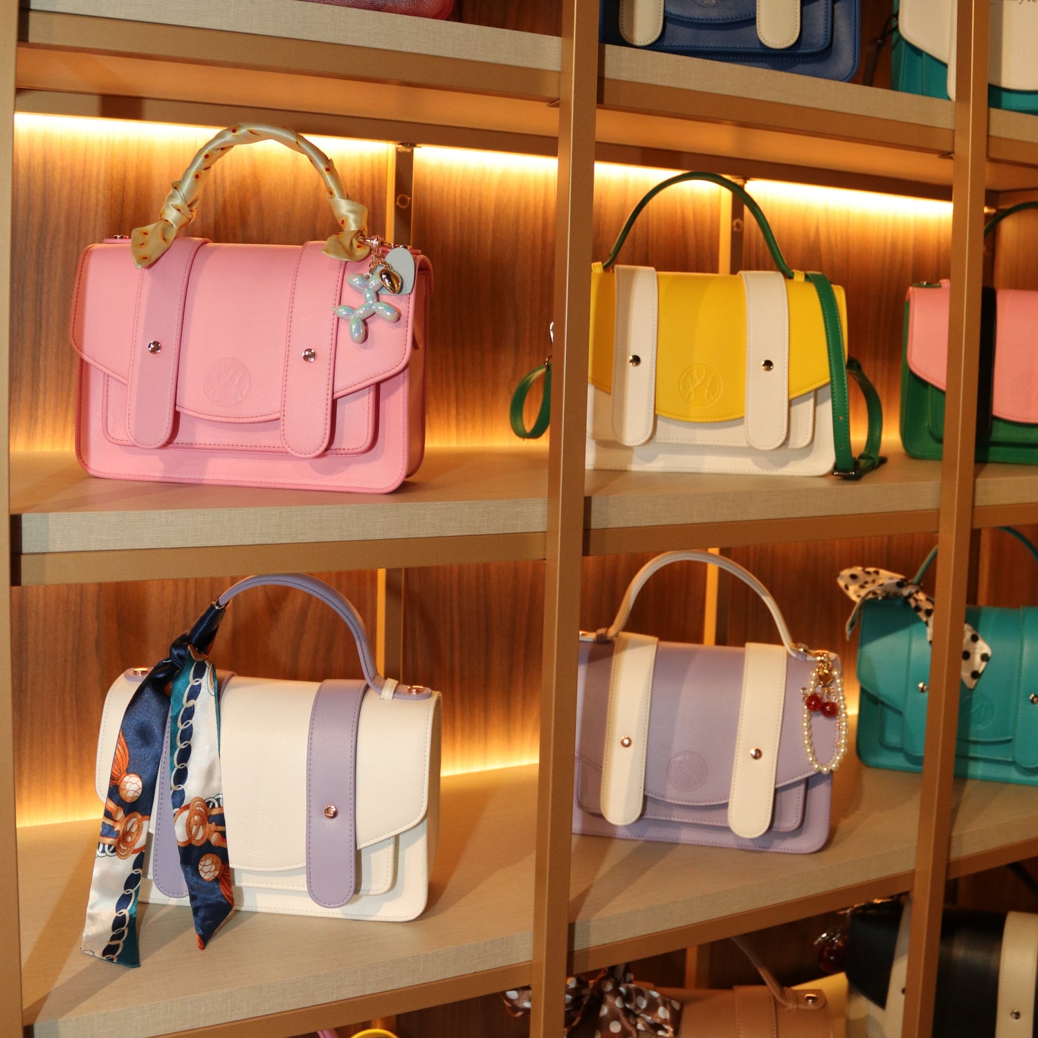 Display of various handbags on a wooden shelf with warm lighting.