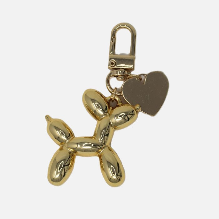 Waterloo Bags gold balloon dog purse charm with a heart tag on a white background